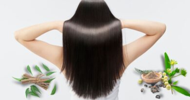 Vrouw met lang, glanzend zwart haar van achteren gezien, omringd door Ayurvedische kruiden zoals amla, neem en poeders voor haarverzorging.