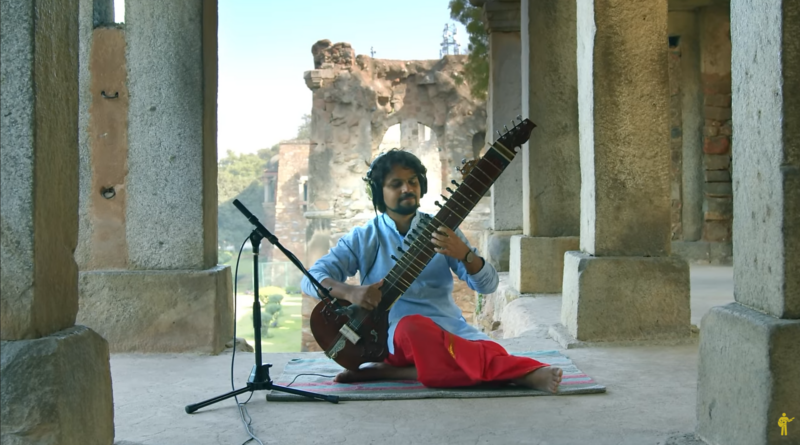 Fly like an eagle. A musician playing the sitar while seated in a meditative pose within the stone pillars of an ancient historical monument.
