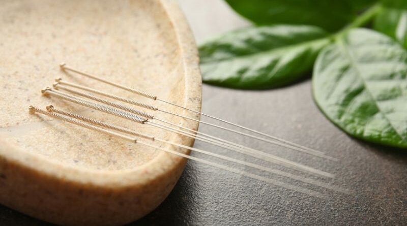 Flinterdunne acupunctuur naaldjes rustend op een natuurstenen schaal met groene bladeren op de achtergrond voor een holistische behandeling van angst.