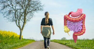 A woman walking on a rural path in nature with a 3D illustration of the human digestive system floating next to her, symbolizing the link between exercise and gut health.
