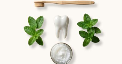 Flat lay compositie van een witte gezonde tand omringd door een bamboe tandenborstel, verse muntblaadjes en een potje kokosolie voor oil pulling op een witte achtergrond.