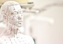 Wit acupunctuurmodel van een menselijk hoofd en torso met aanduidingen van meridianen en drukpunten.
