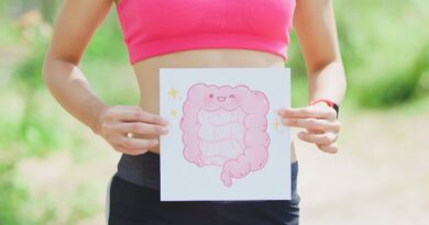 Een vrouw in sportkleding houdt een tekening van vrolijke, gezonde darmen voor haar buik om de link tussen darmgezondheid en mentaal welzijn te symboliseren.