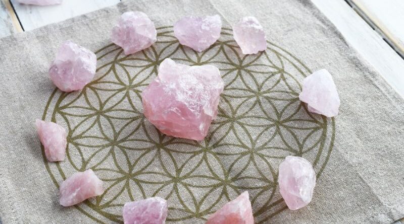 Rozenkwarts edelstenen in een cirkel op een Flower of Life onderzetter voor spirituele groei en zelfliefde.