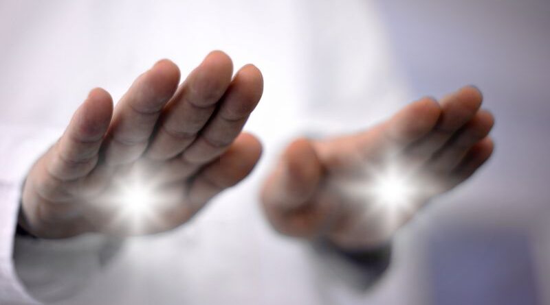 Close-up of a practitioner's hands projecting bright white light during a non-invasive pranic healing energy work session.