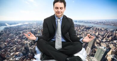 A calm businessman in a black suit meditating with closed eyes on a cloud above a busy cityscape, representing how to stay grounded, drop your guard, and stop being defensive during stressful interactions.